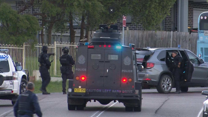 Tactical police and an armoured police van are stationed on a suburban street in Wyong.