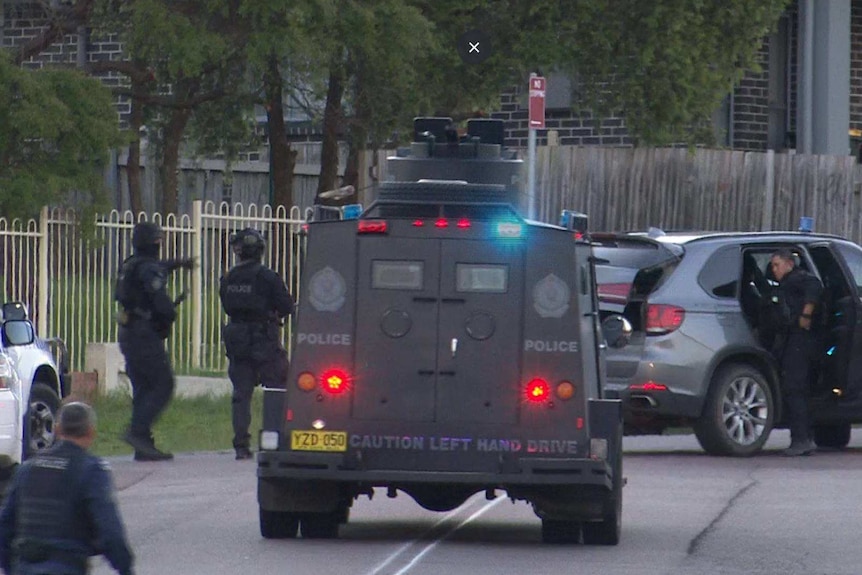Tactical police and an armoured police van are stationed on a suburban street in Wyong.