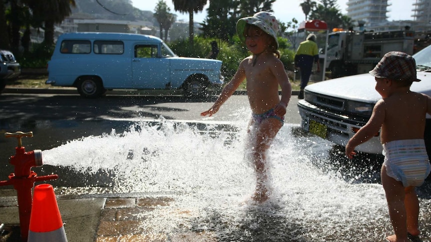 Toddlers play in water from a fire hydrant