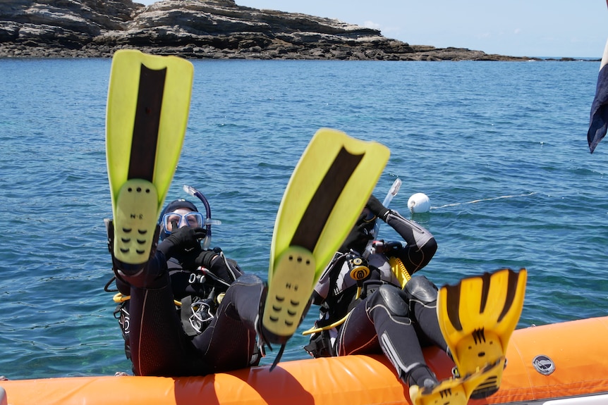Scuba divers going overboard a raft.
