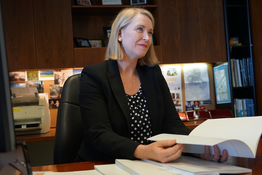 Nicole Manison sitting at a desk, flipping through budget papers.