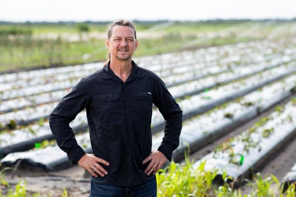 man in black shirt and hands on hips smiles at camera