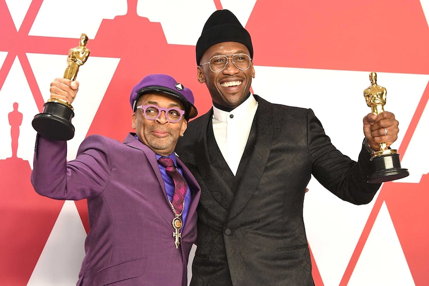 Two men hold up their Oscar awards