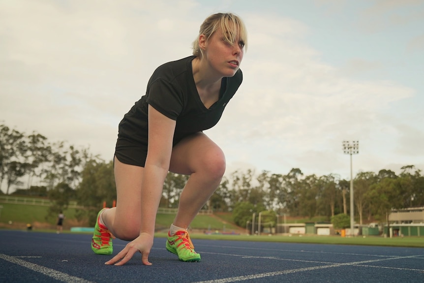 A crouches on a running track.