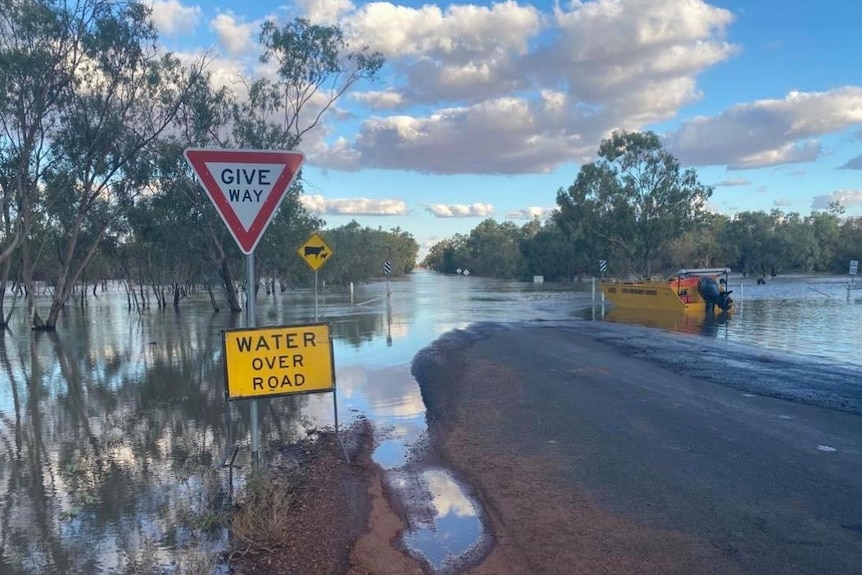 A sign saying "road closed" in front of a flooded road
