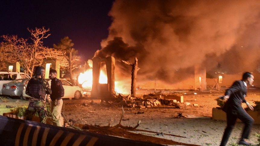 A car park is shown aflame, and police and a soldier are seen at the blast site.