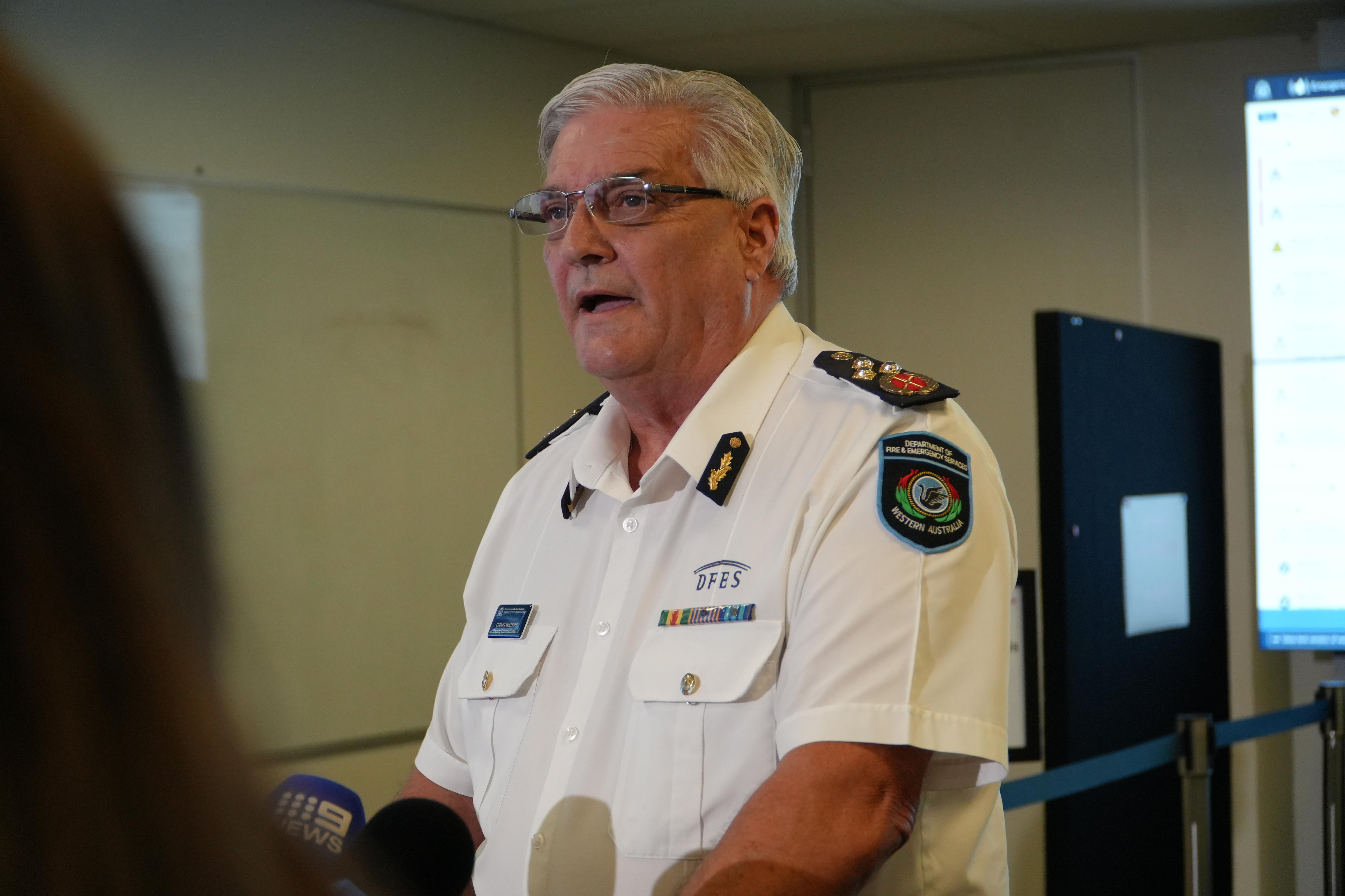 Офицер в белой форме из Департамента пожарной охраны и экстренных служб беседует со СМИ. 