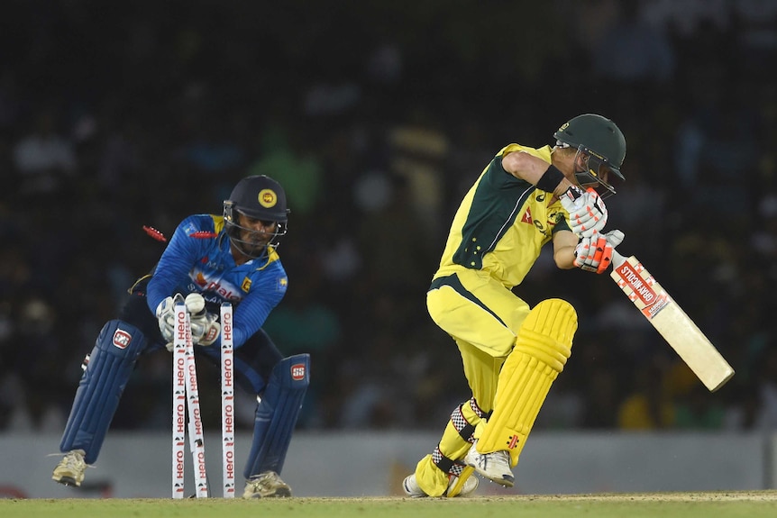 Australia's David Warner (R) is bowled as Sri Lankan wicketkeeper Kusal Perera looks on in Dambulla.