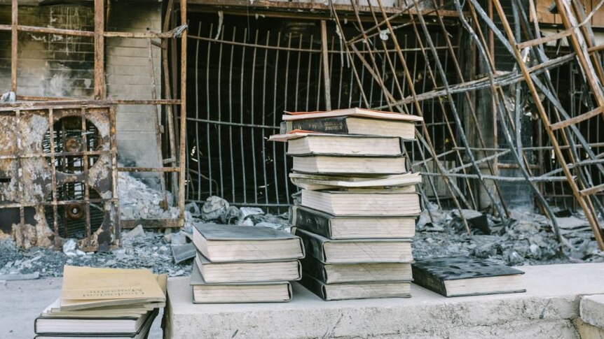 Books stacked on top of each other in front of a destroyed building
