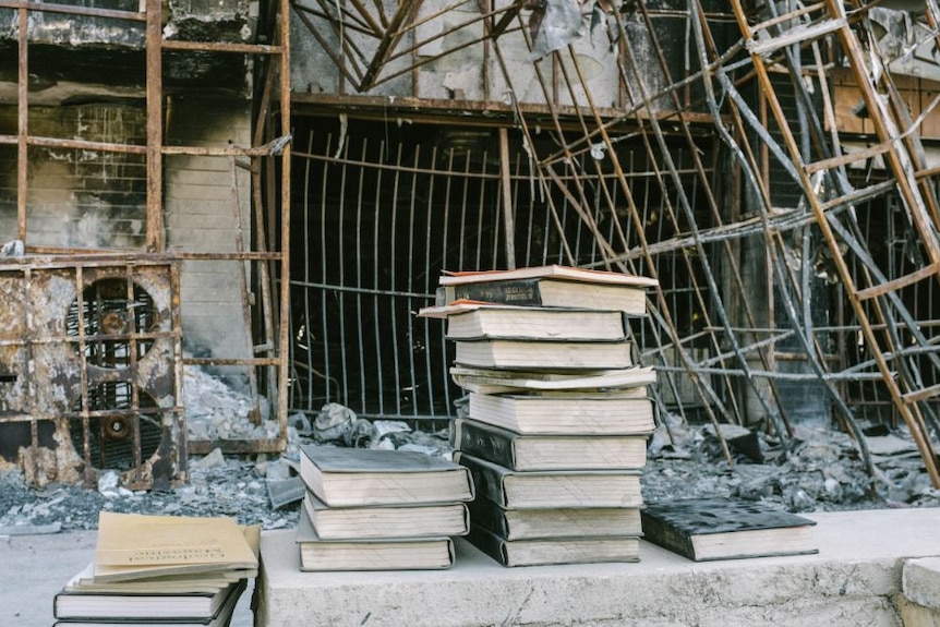 Books stacked on top of each other in front of a destroyed building