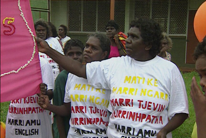 People wearing t-shirts with slogans on them hold banners