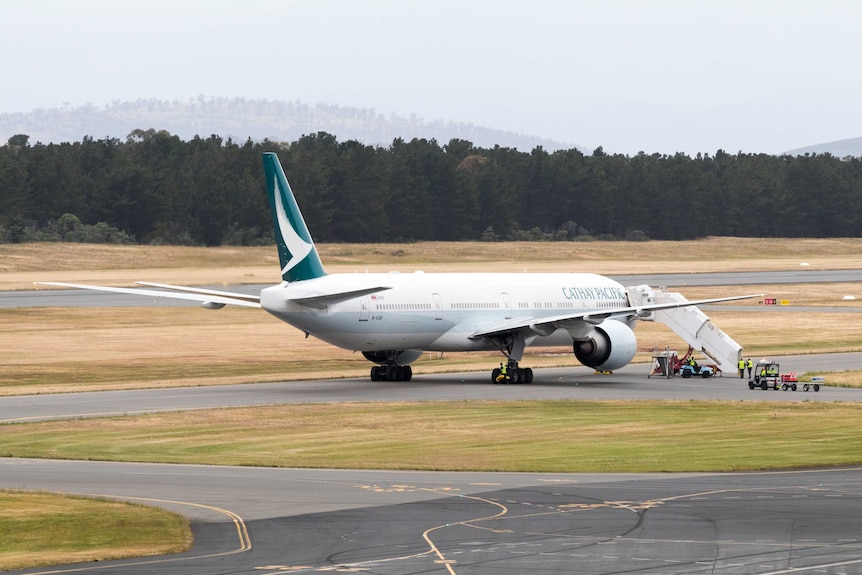 A white Cathay Pacific freight aeroplane on the tarmac being loaded.