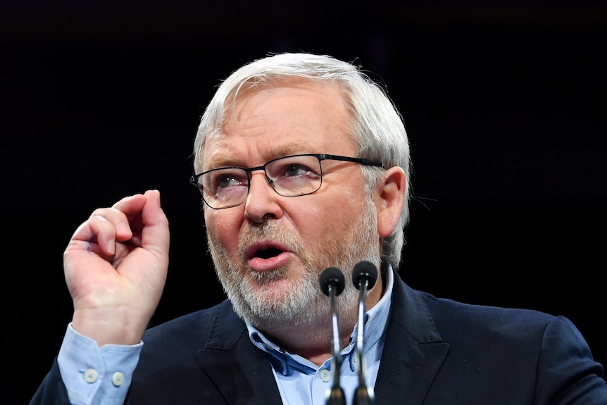 Prim-plan cu Kevin Rudd vorbind în spatele a două microfoane și arătând cu mâna dreaptă.