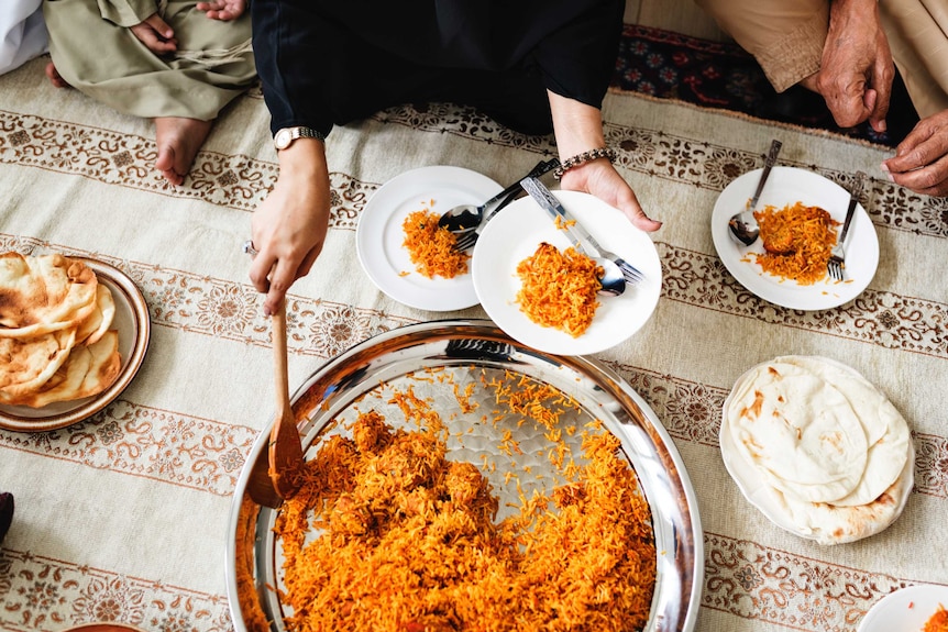 A person putting biryani on a plate