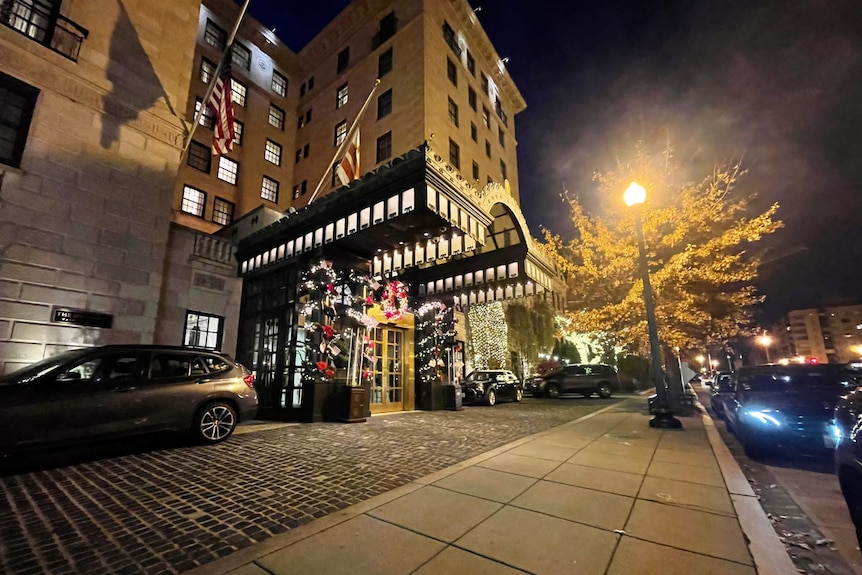 A night time external view of the entrance to a hotel, adorned with Christmas decorations.