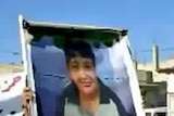 A Syrian man holds a photo of 13-year-old boy, Hamza al-Khatib, during his funeral