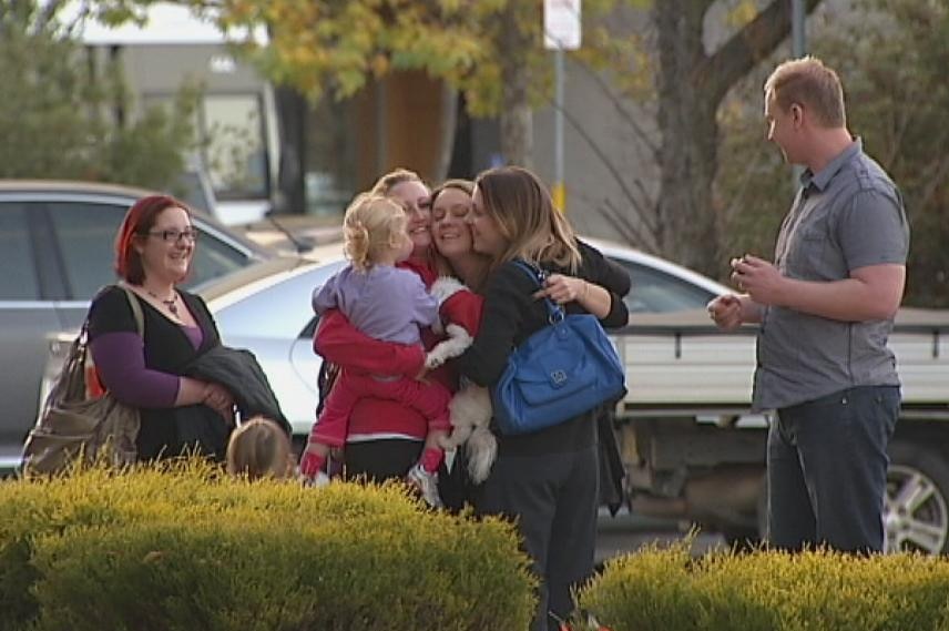 Friends of Andre Le Dinh's family hug outside the ACT Supreme Court.