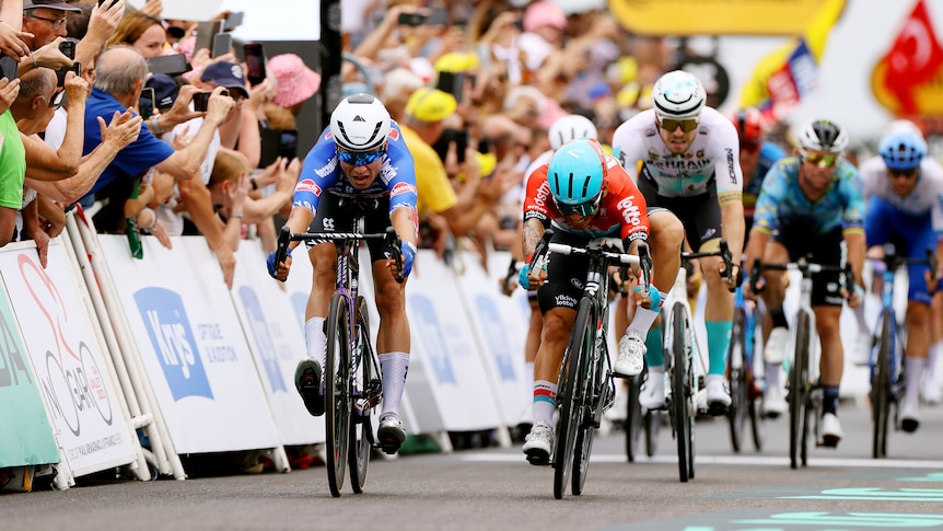 Australian cyclist Caleb Ewan (front right) grimaces as he lunges for the line but is beaten by a rider to the left of screen. 
