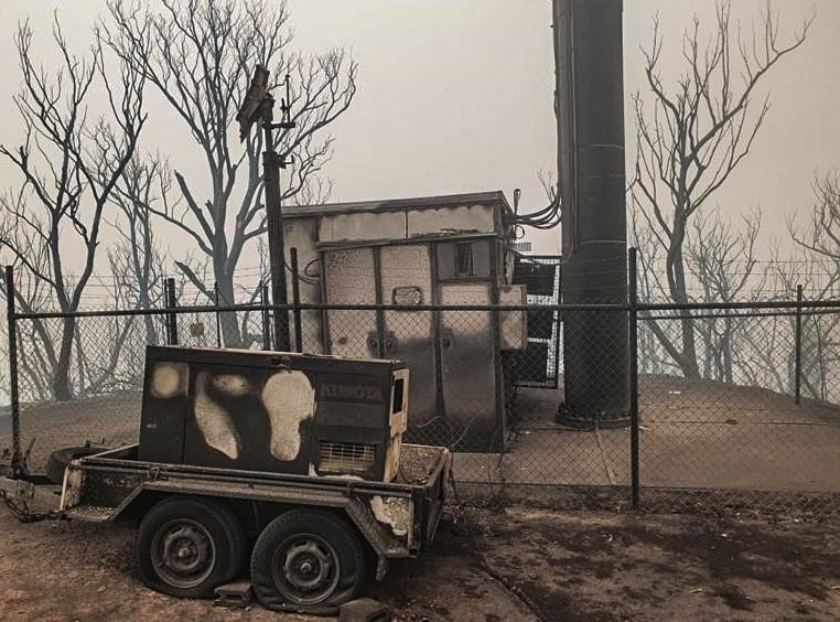 The bottom of a phone tower, on top of a burnt out hill, everything is black and grey.