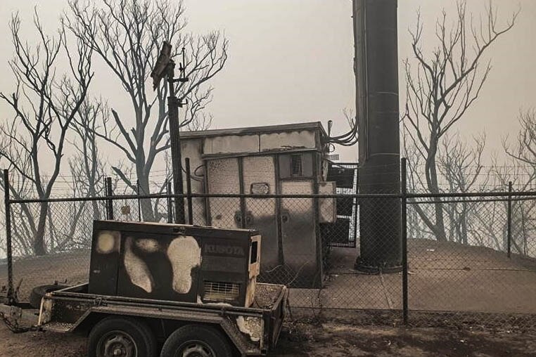 The bottom of a phone tower, on top of a burnt out hill, everything is black and grey.