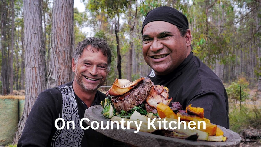 Comic and performer Derek Nannup and Indigenous Chef Mark Olive holding a plate of food and smiling at the camera