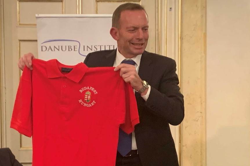 A man holds a red t'shirt up to the camera