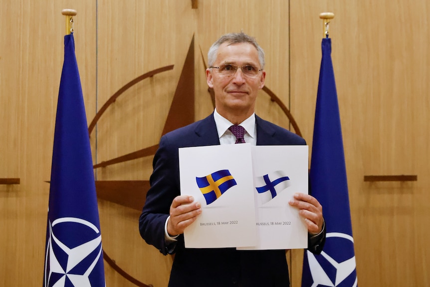 Man holds up two documents.