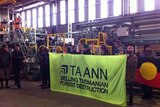 Forest activists hold a sign inside Ta Ann's Smithton sawmill.
