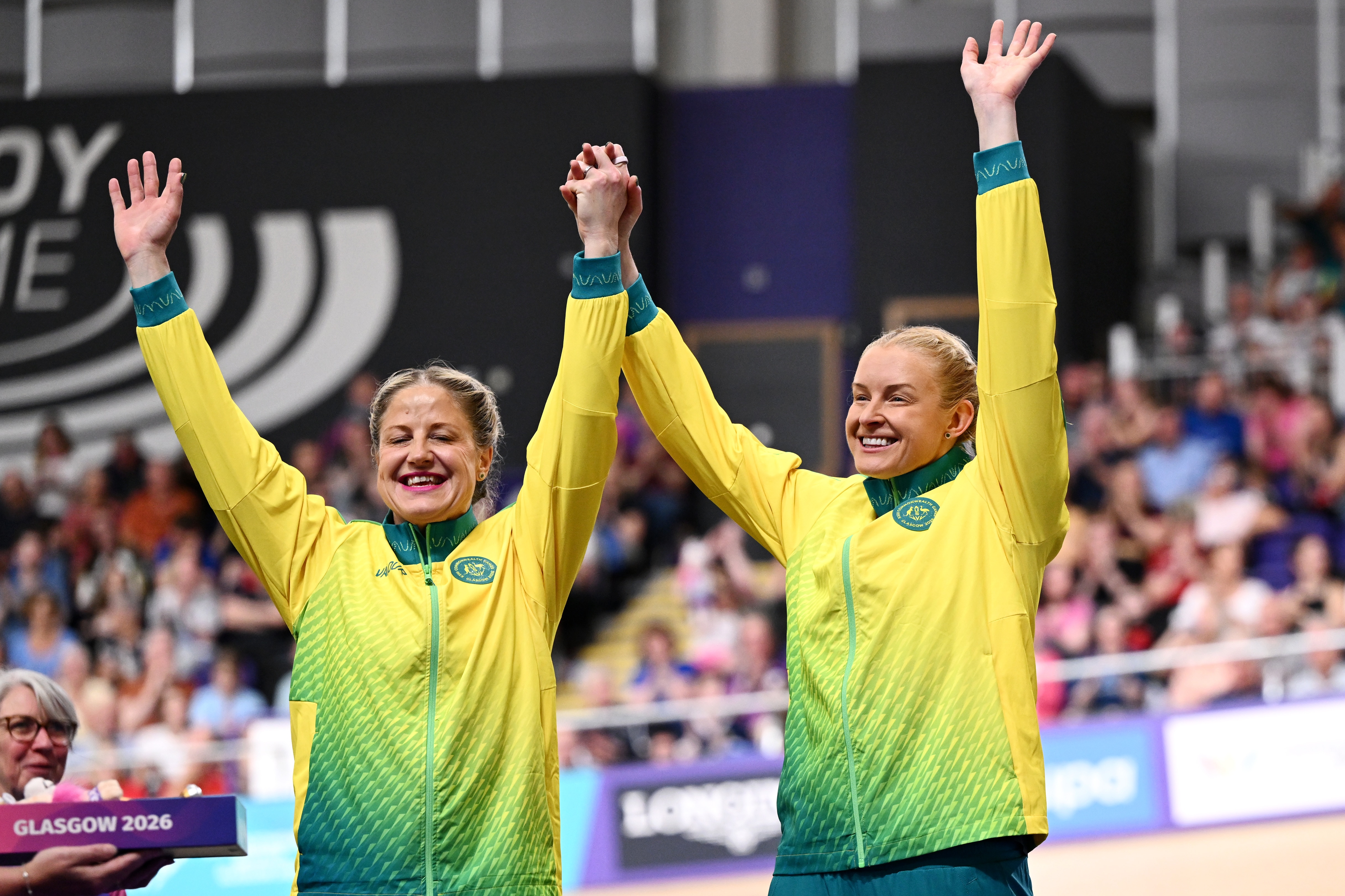 Jacqui Mengler-Mohr and Jessica Gallagher raise their hands on the podium in Glasgow.