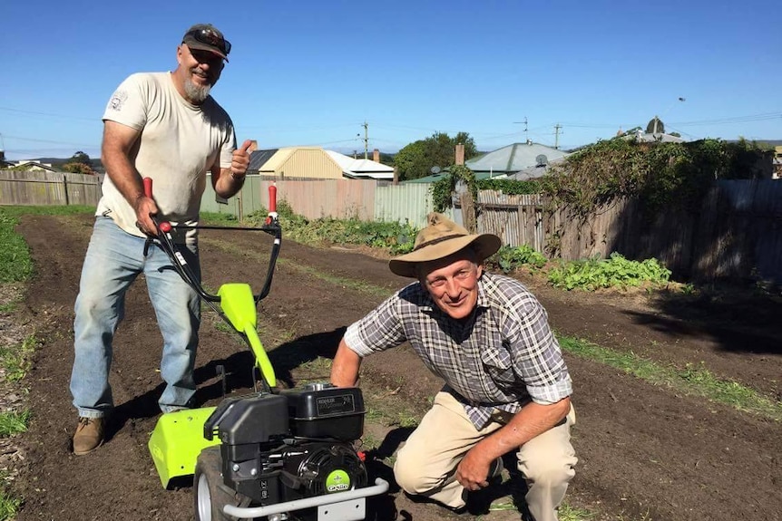 Darren Harrison and another gentleman in the Taree Community garden sewing flowerbeds.
