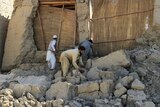 Afghan men clear bricks from a house after earthquake