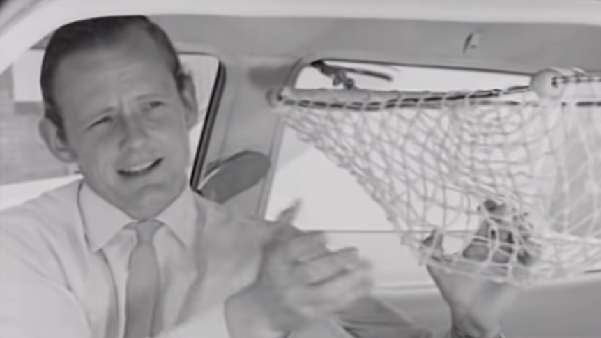 Black and white shot of Michael Henderson sits in a car fitted with a loose string net — a baby hammock from the era