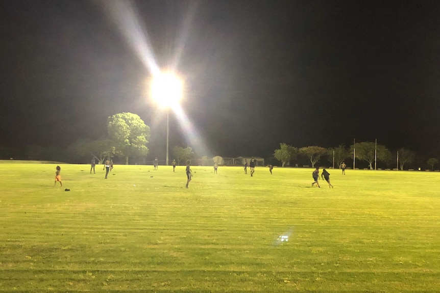 The Halls Creek grass oval at night with lights shining on the field.