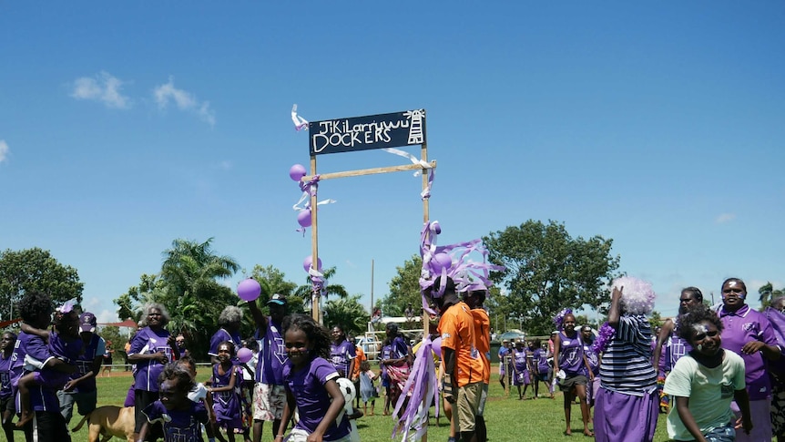 Jikilarruwu Dockers fans run onto the field as the football grand final gets underway.