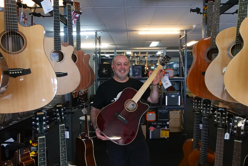 man holding guitar standing and smiling