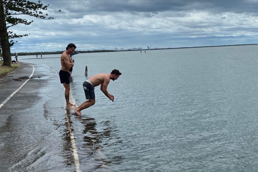 A man jumps into the water beside a footpath.