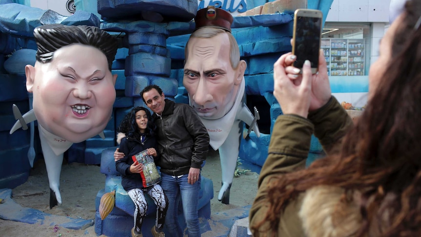 People take pictures by statues of North Korean leader Kim Jong Un and Russian President Vladimir Putin