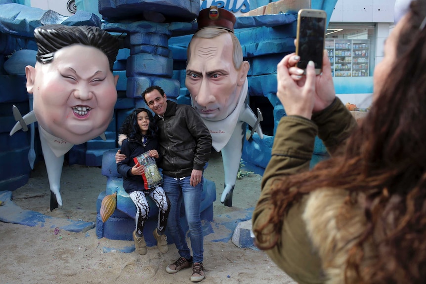 People take pictures by statues of North Korean leader Kim Jong Un and Russian President Vladimir Putin