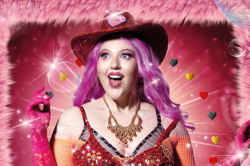 A woman with pink hair has an excited expression. She is wearing a sequinned red cowboy hat and hot pink lace gloves. 