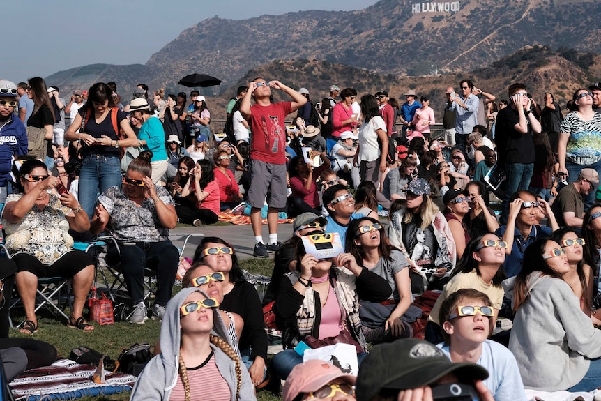 A crowd gathers at the Griffith Observatory in front of the Hollywood sign in Los Angeles to view the eclipse.