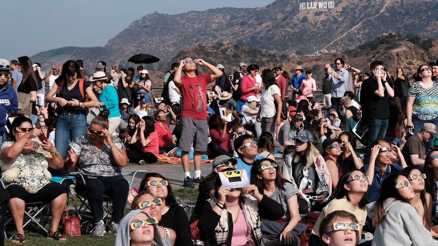 A crowd gathers at the Griffith Observatory in front of the Hollywood sign in Los Angeles to view the eclipse.