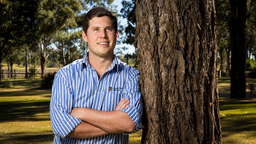 Toby Locke stands next to a tree.