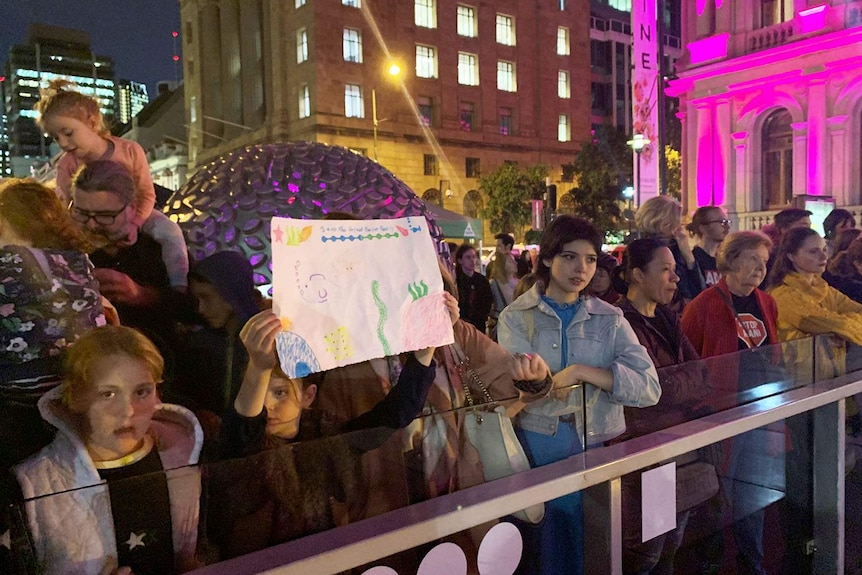Hundreds of anti-Adani protesters, with a girl in front with a child's reef drawing, gathered at Brisbane Square in the CBD.