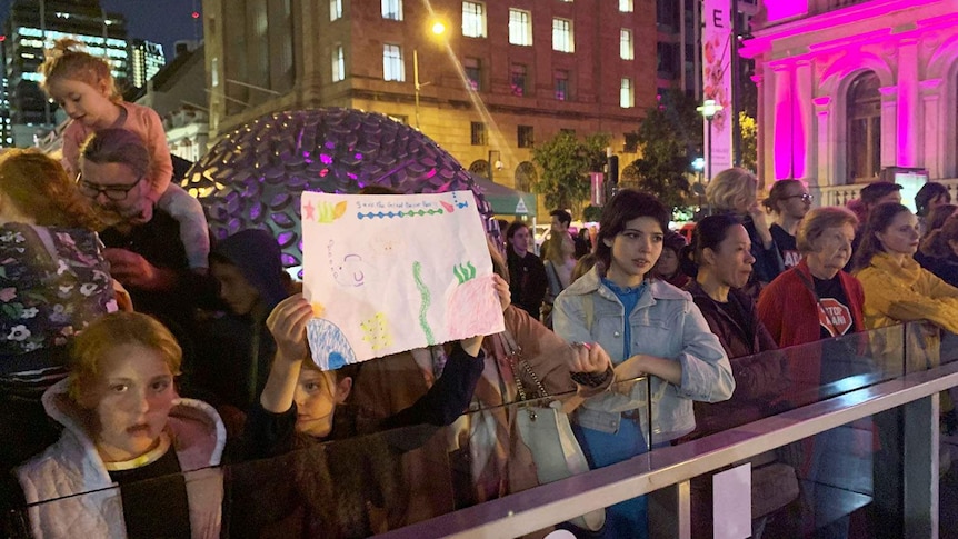 Hundreds of anti-Adani protesters, with a girl in front with a child's reef drawing, gathered at Brisbane Square in the CBD.