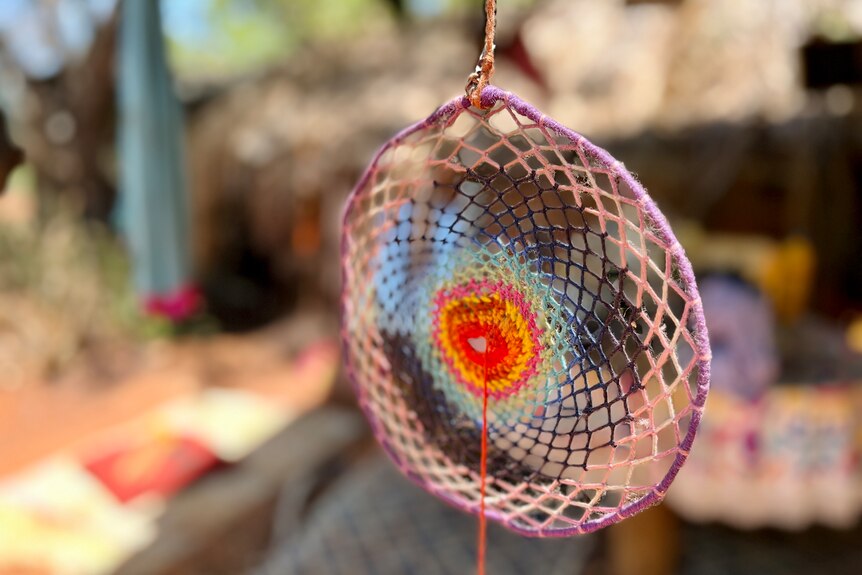 A colourful circle shape stitched from wool hangs in the sunshine