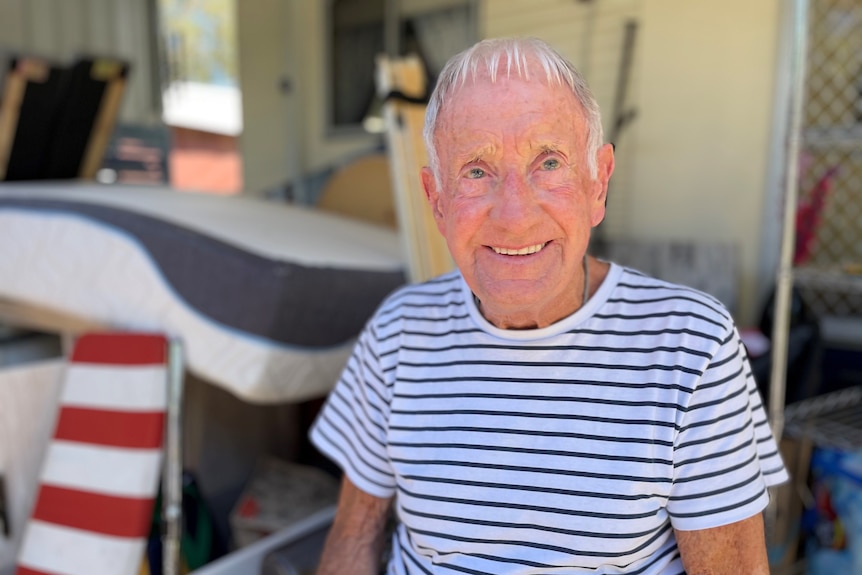 Elderly resident of a caravan park sitting in front of his damaged belongings