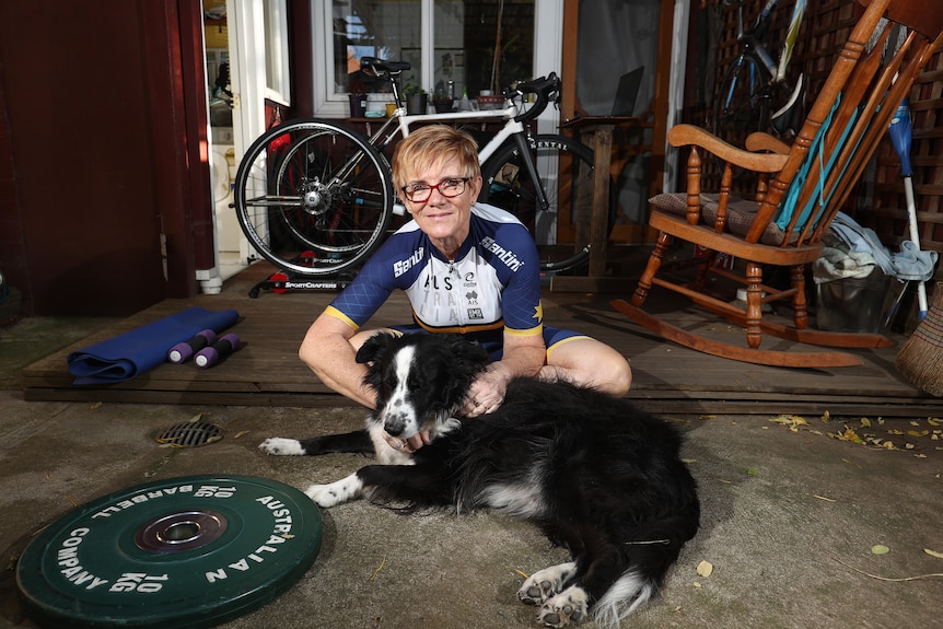 Woman sitting in her backyard with her dog in her cycling uniform