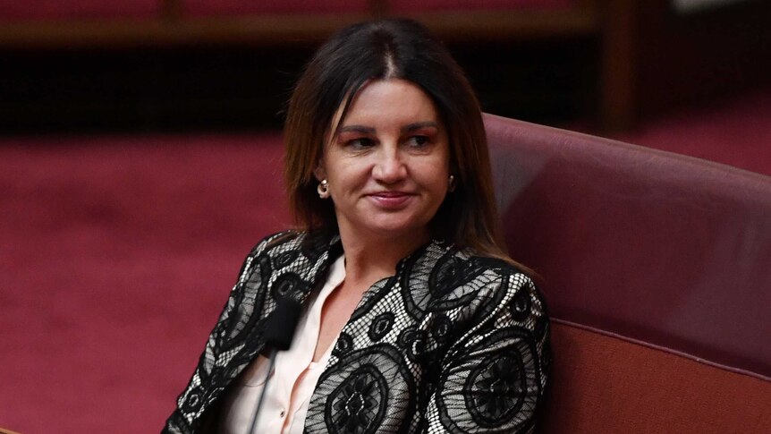Senator Jacqui Lambie sits in the Senate and looks to the side.