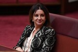 Senator Jacqui Lambie sits in the Senate and looks to the side.