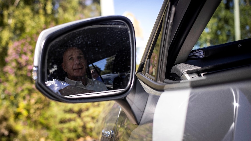 A man's face reflected in a car mirror